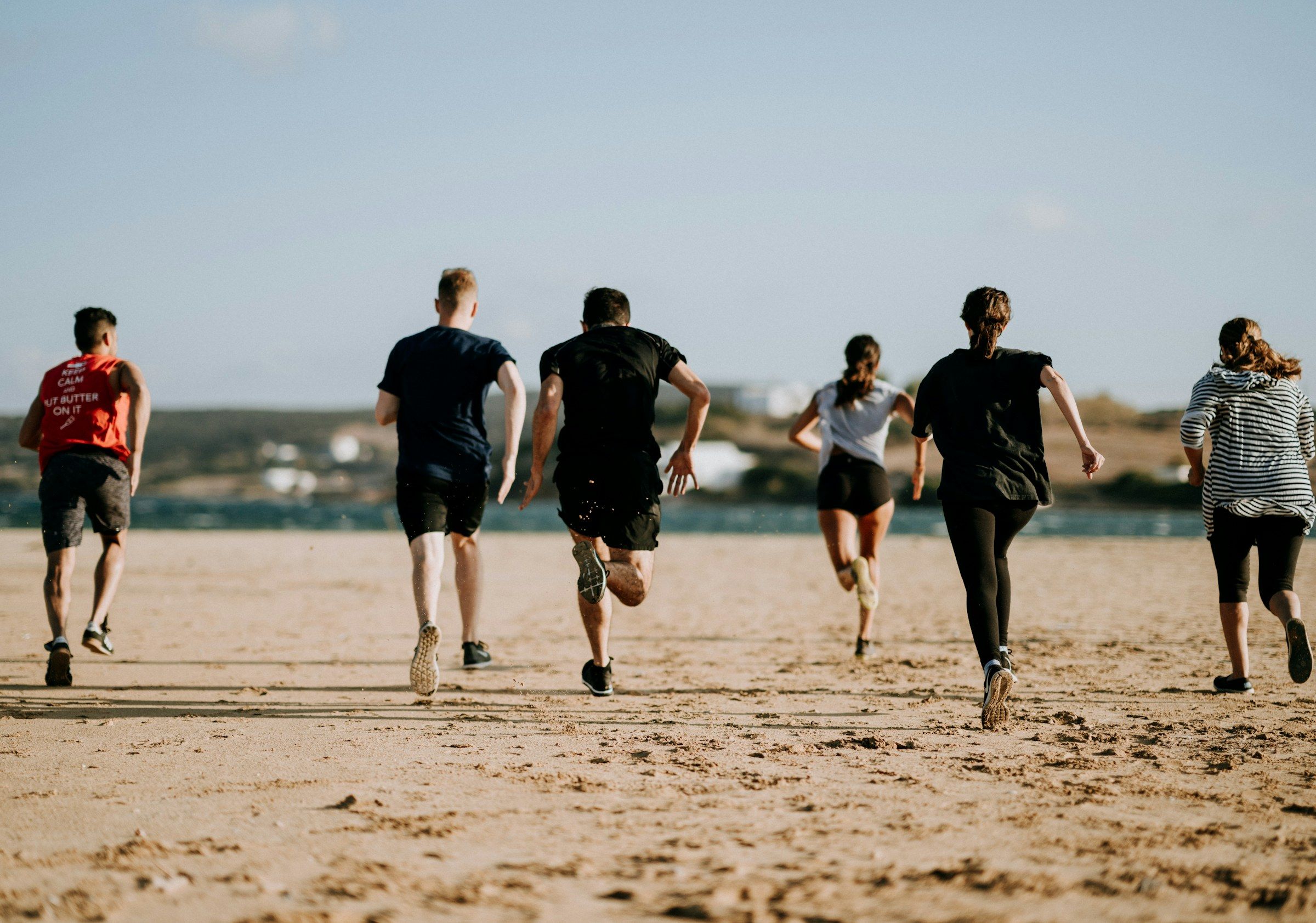 Un groupe court sur une plage de sable